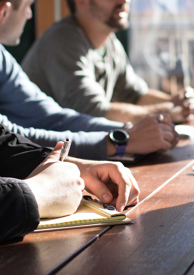 mens hands on table some taking notes